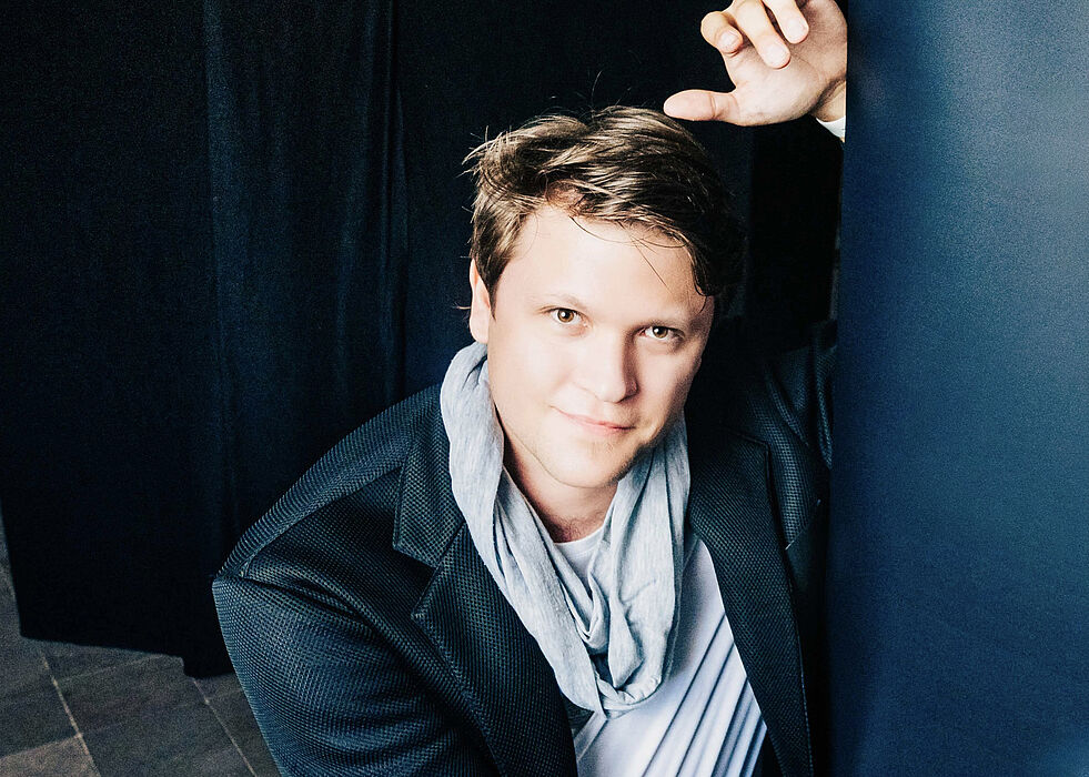 A young man leans against the side of a board. 