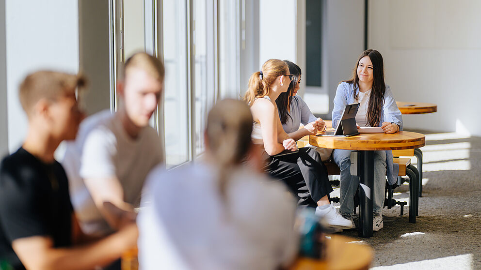 Studierende unterhalten sich in Gruppen. 